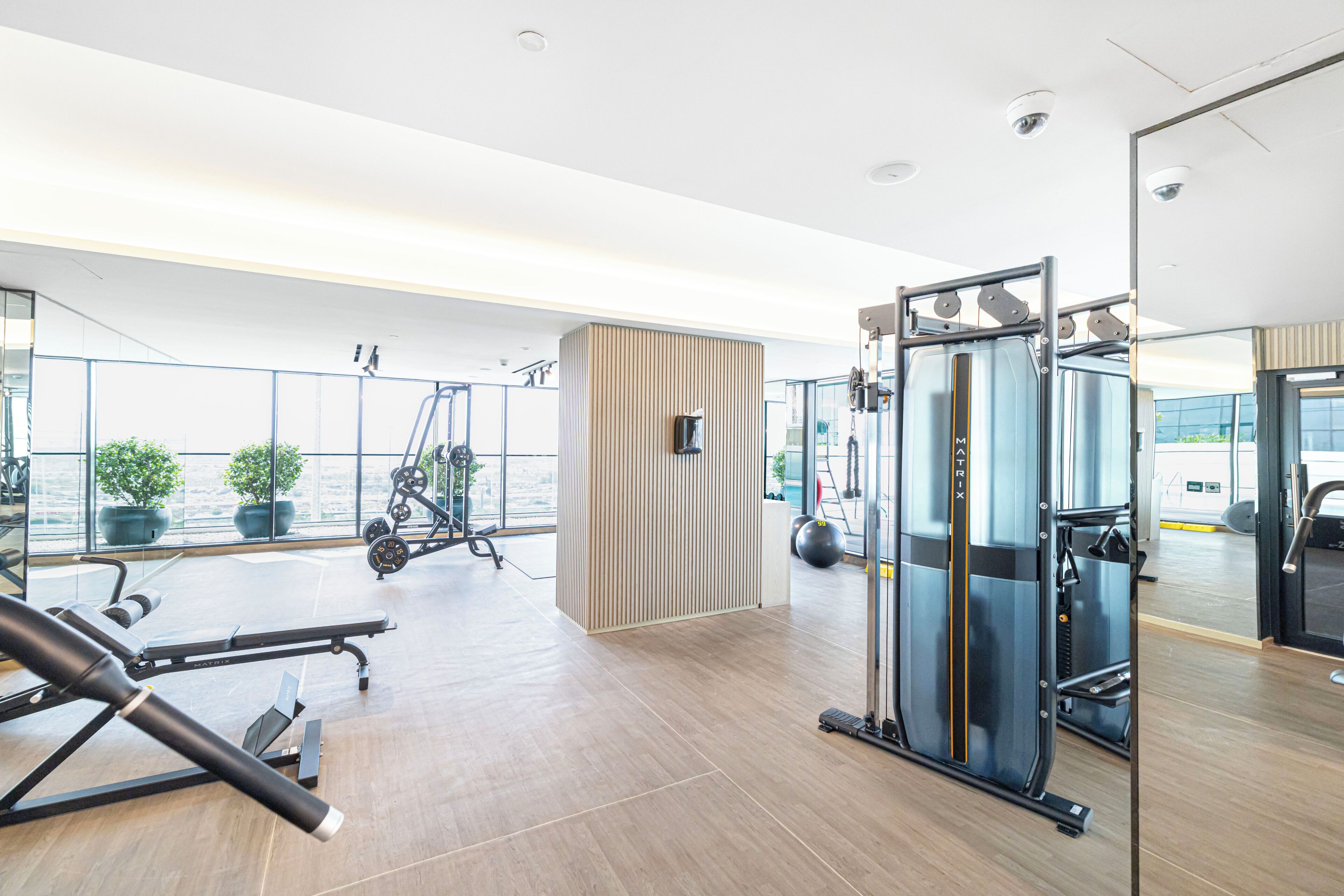 Een moderne sportschool met trainingsapparatuur, grote ramen en uitzicht op buiten.