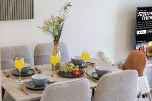 Een eettafel gedekt met borden, kommen, bestek en glazen jus d'orange.