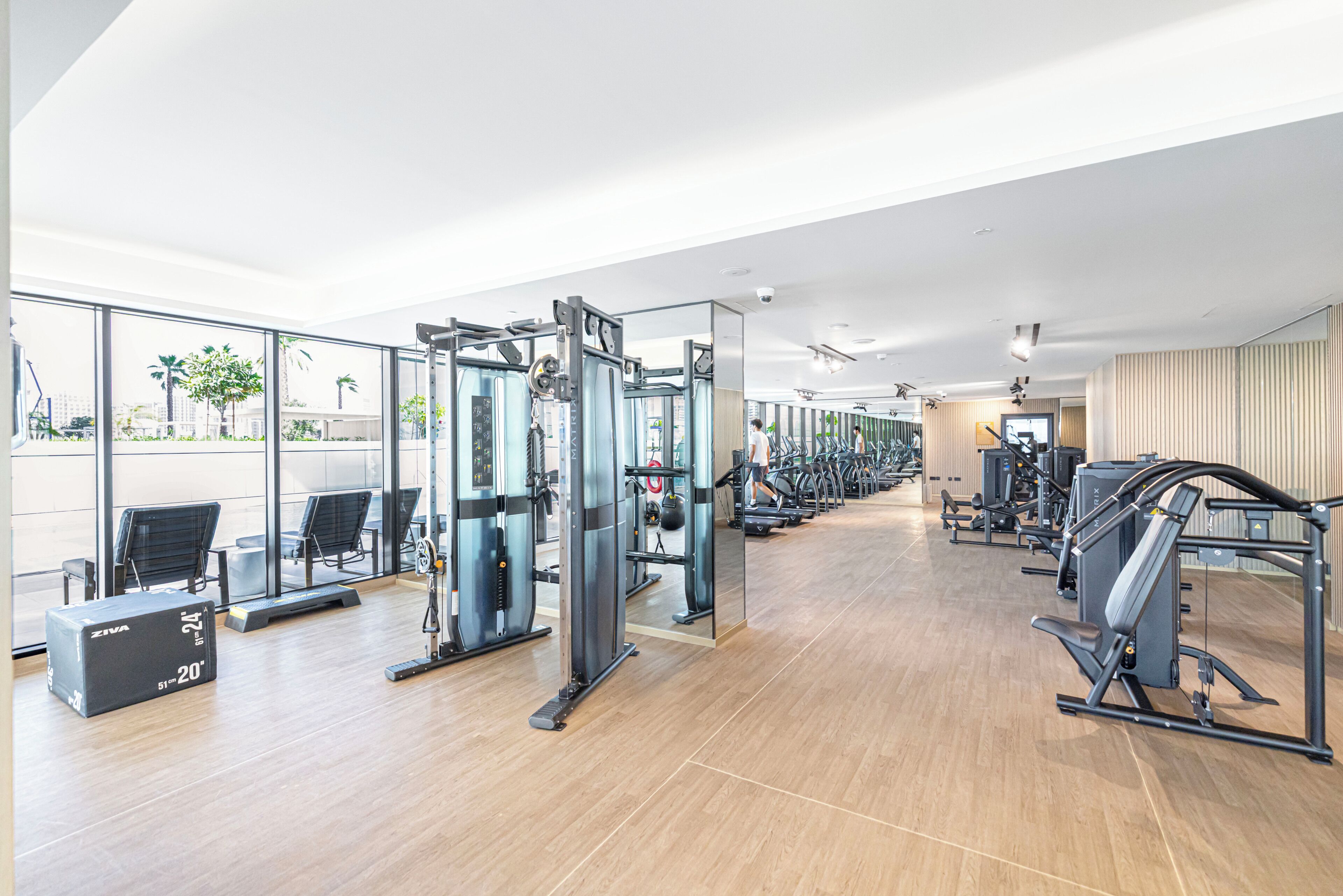Une salle de sport moderne dotée de divers équipements d’exercice, de grandes fenêtres et d’un aménagement propre et spacieux.