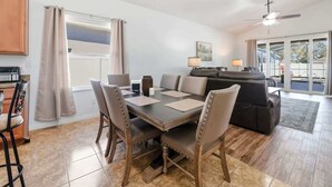 Un salon moderne comprenant un coin repas, une cuisine, un ventilateur de plafond et une vue dégagée grâce à de grandes fenêtres.