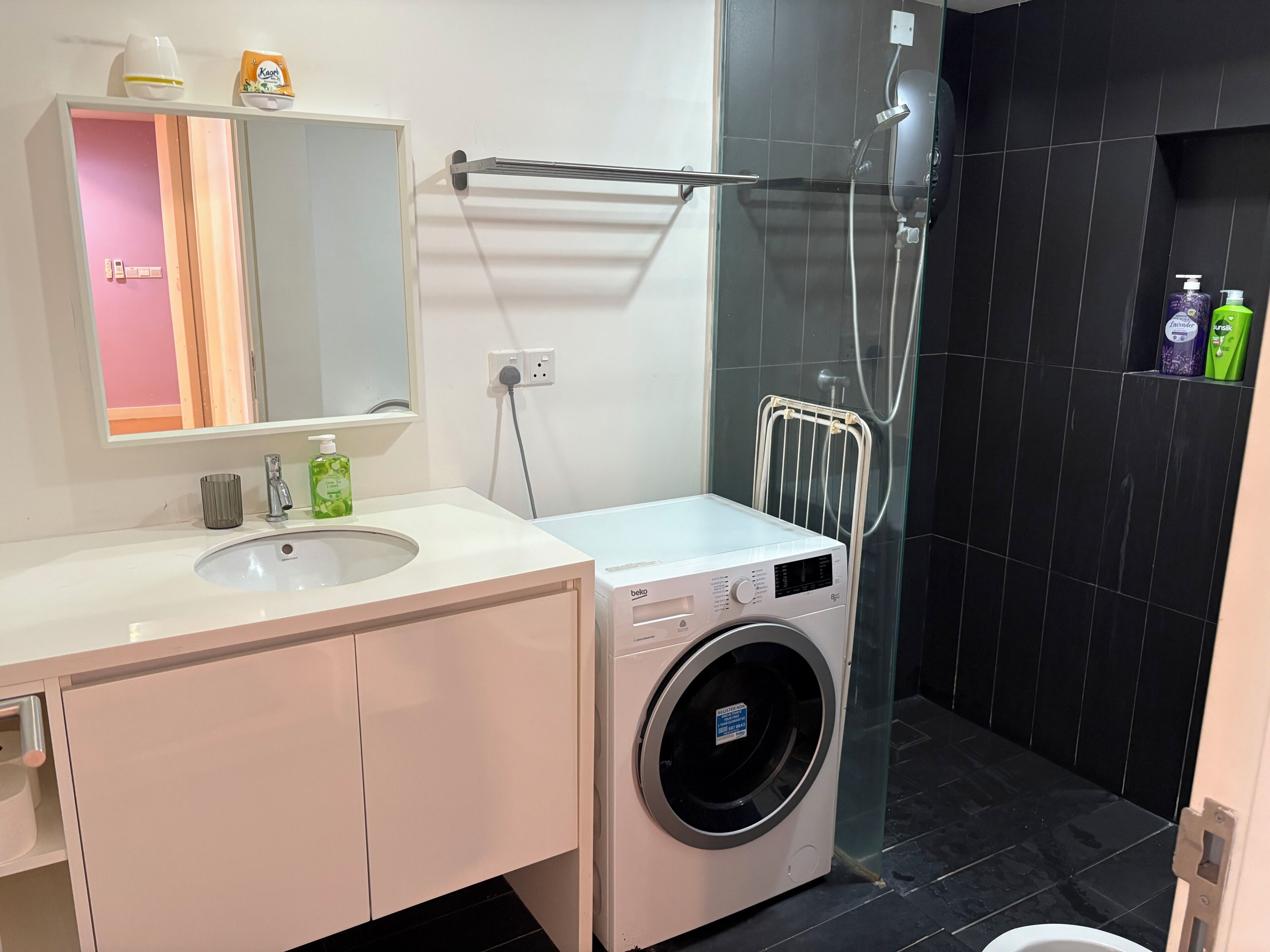 Ein modernes Badezimmer mit einem weißen Waschbecken, einem Spiegel und einer integrierten Waschmaschine.