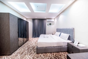 Una habitación de hotel moderna con una cama grande, un armario, una mesita de noche y un techo con tragaluces.