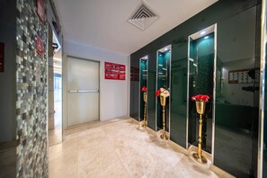 A hotel lobby with a tiled floor, a reception desk, and a glass partition with a red sign. - Orvana Prime (Jeddah)