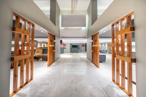 Un pasillo con divisiones de madera, un mostrador de recepción y una zona de estar con sofás.