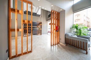 Un interior moderno con un separador de madera, un radiador, un sofá gris y vistas al exterior.
