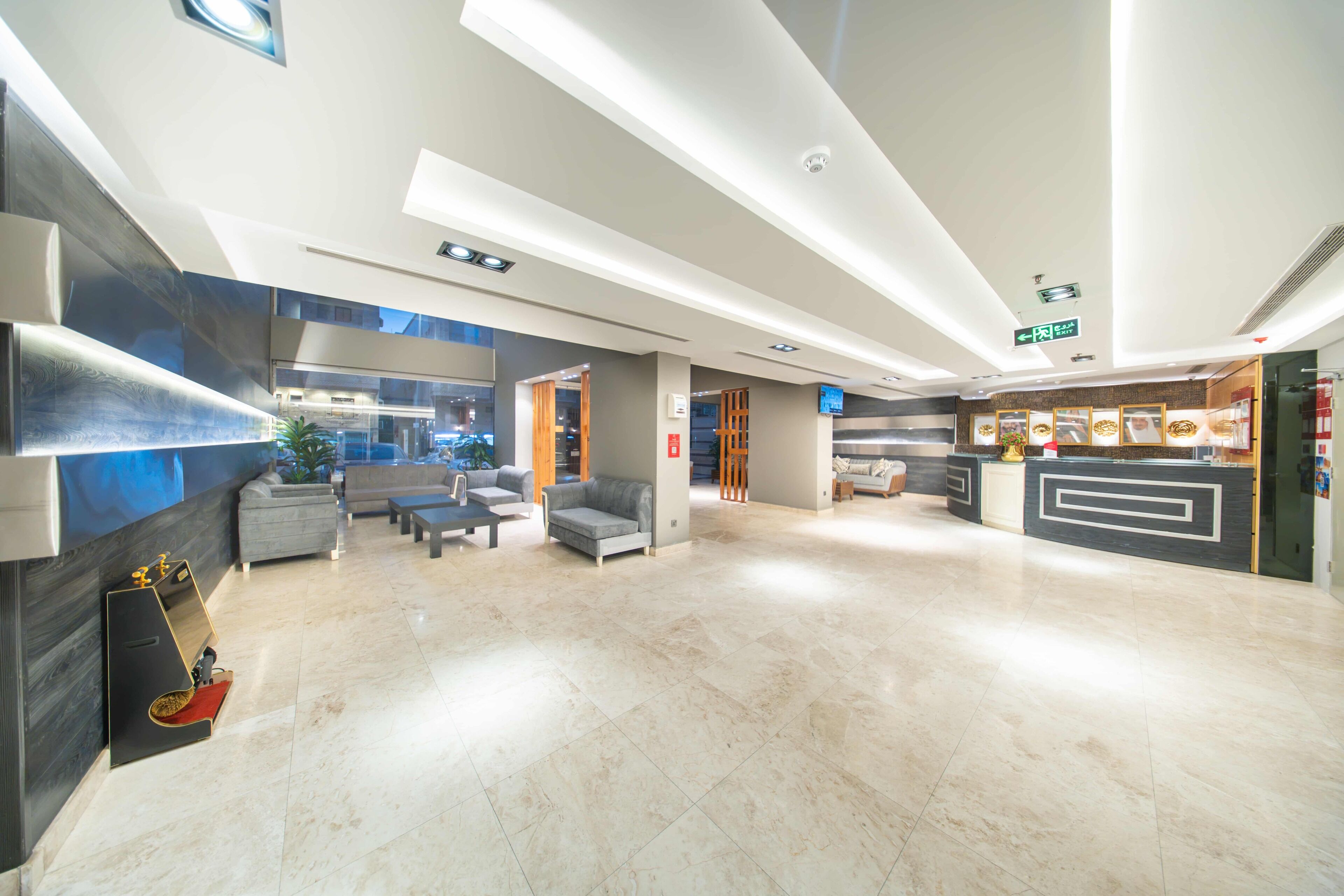 A spacious lobby with a reception desk, seating area, and a view of the street outside.