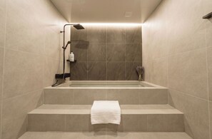 Un baño moderno con una bañera, ducha y una toalla sobre los escalones.