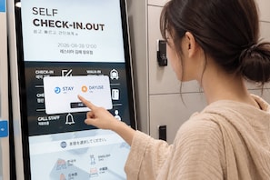 A woman interacting with a self-check-in kiosk at a hotel.