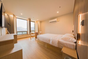 Una habitación de hotel moderna con cama, escritorio y vista al mar.