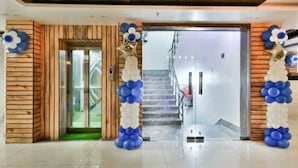 Un hall de hotel con una pared de madera, una entrada por una puerta de cristal y una escalera que conduce a los pisos superiores.