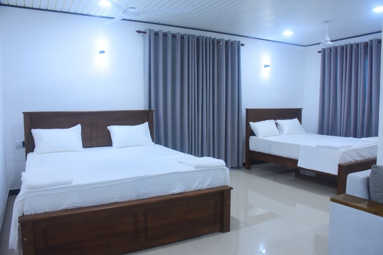 A hotel room with two single beds, a wooden headboard, and a small seating area with a table.