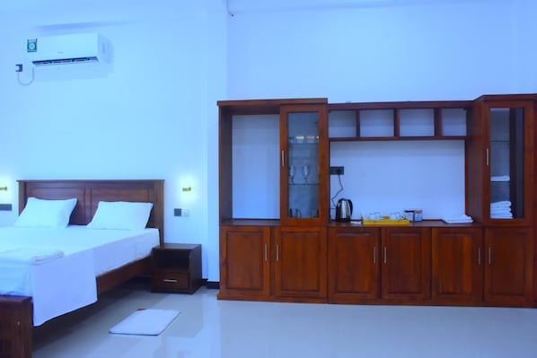 A hotel room with a bed, a wooden wardrobe, and an air conditioning unit.