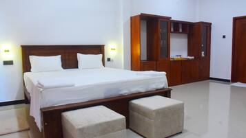 Quarto de hotel com cama, guarda-roupa e um banco.