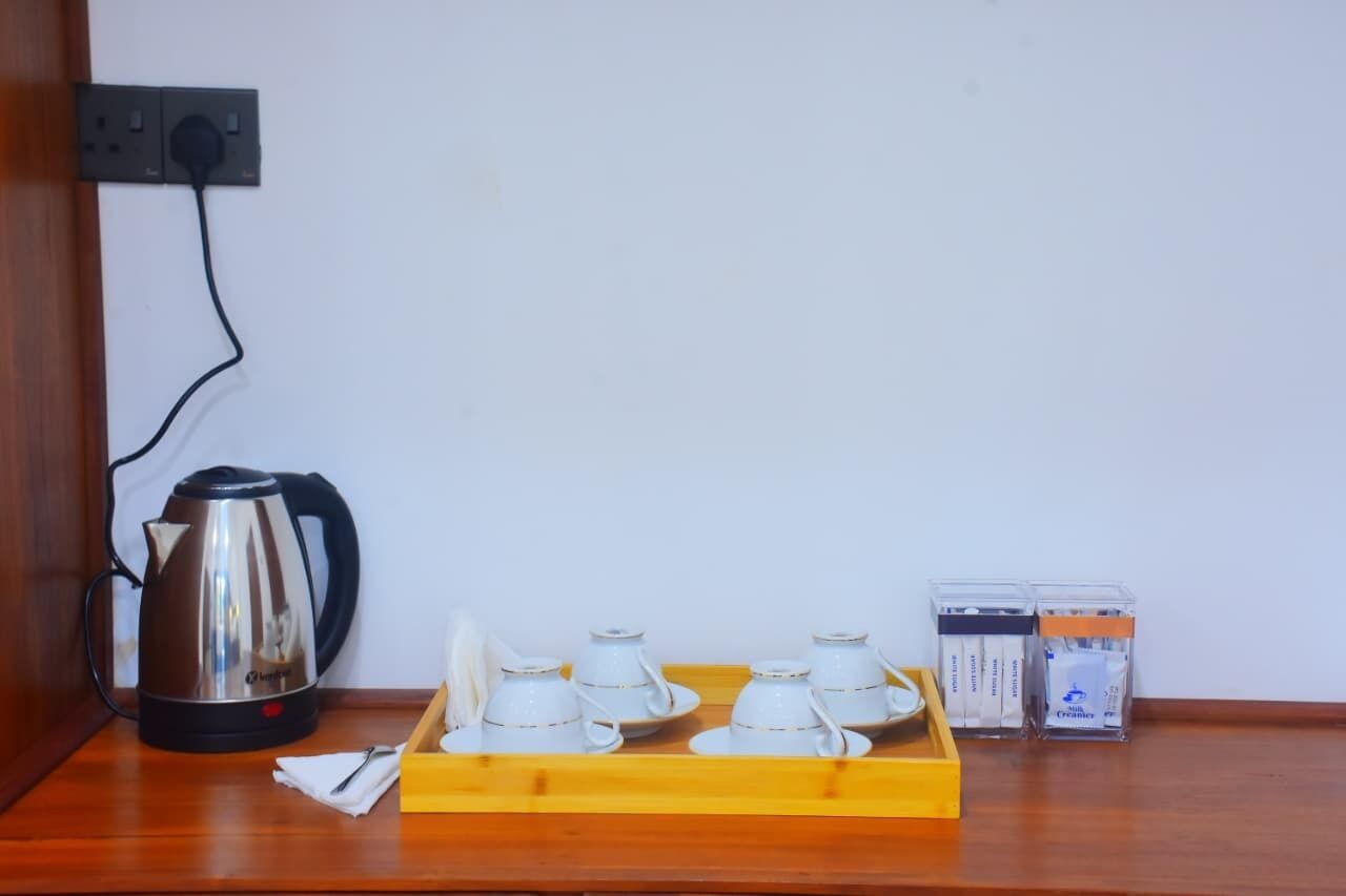 A kitchen area with a kettle, tea cups, and cream containers on a wooden tray.