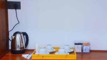A kitchen area with a kettle, tea cups, and cream containers on a wooden tray.