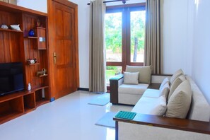 Una sala de estar con un sofá, un televisor y un mueble de madera.