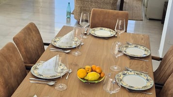 Comedor con mesa de madera lista para una comida, rodeada de sillas.