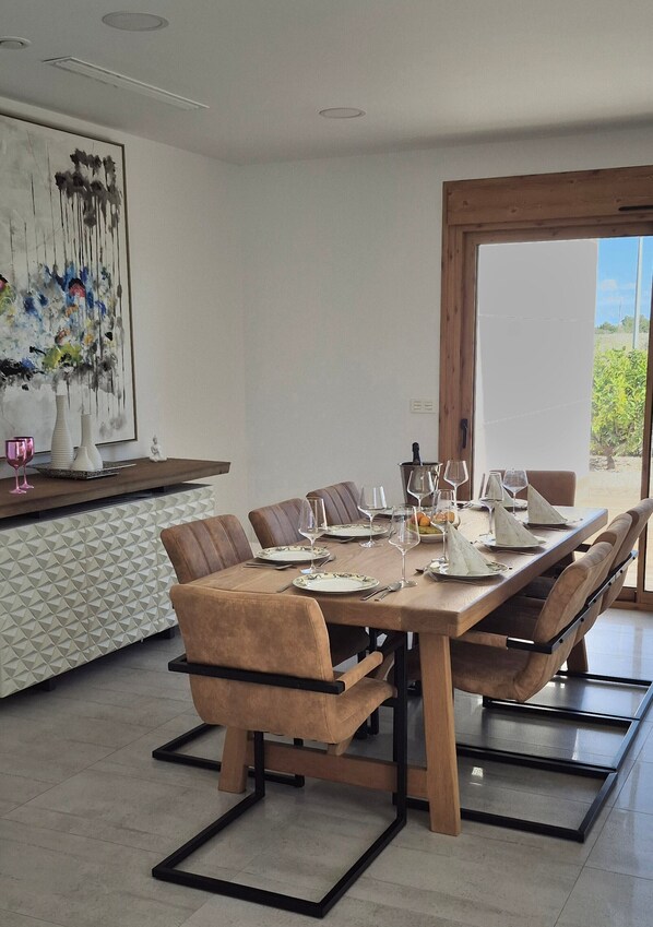 A dining area with a wooden table set for four, surrounded by cushioned chairs.