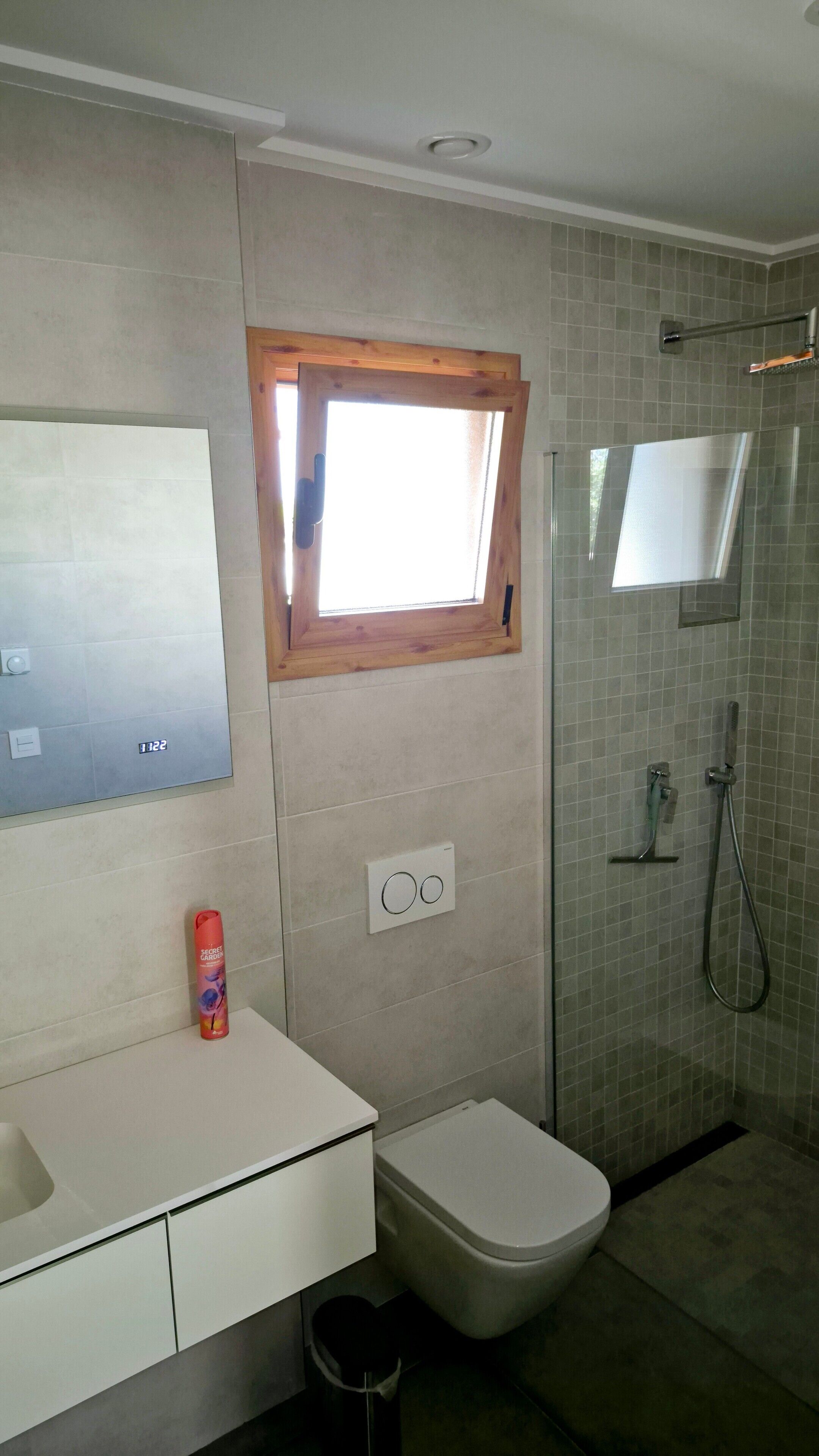 Een badkamer met toilet, wastafel, douche en een raam.