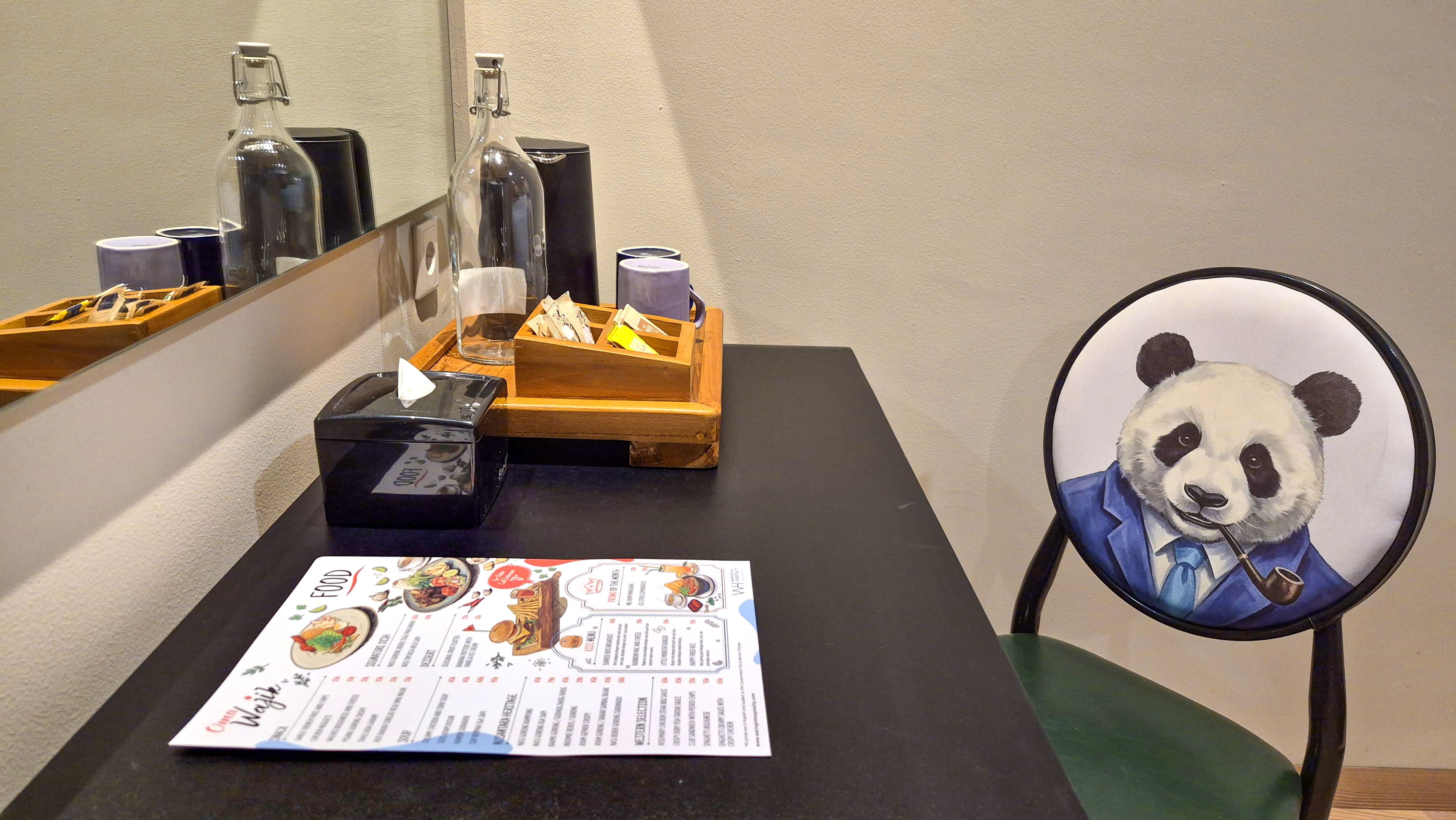Una mesa con un menú, una caja de pañuelos, una caja de madera y una botella de vidrio.