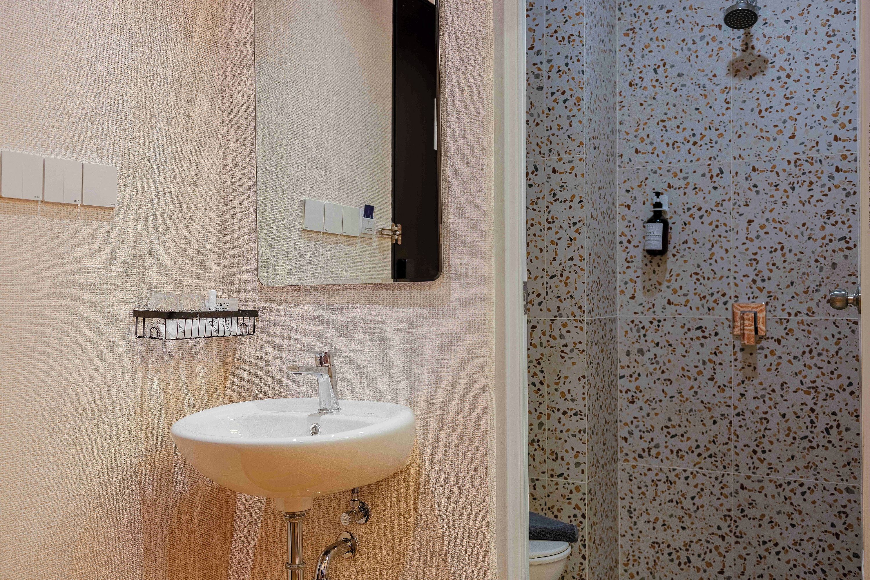 A bathroom with a sink, mirror, and shower.