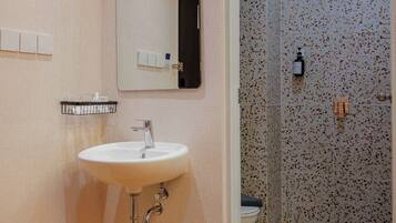 A bathroom with a sink, mirror, and shower.