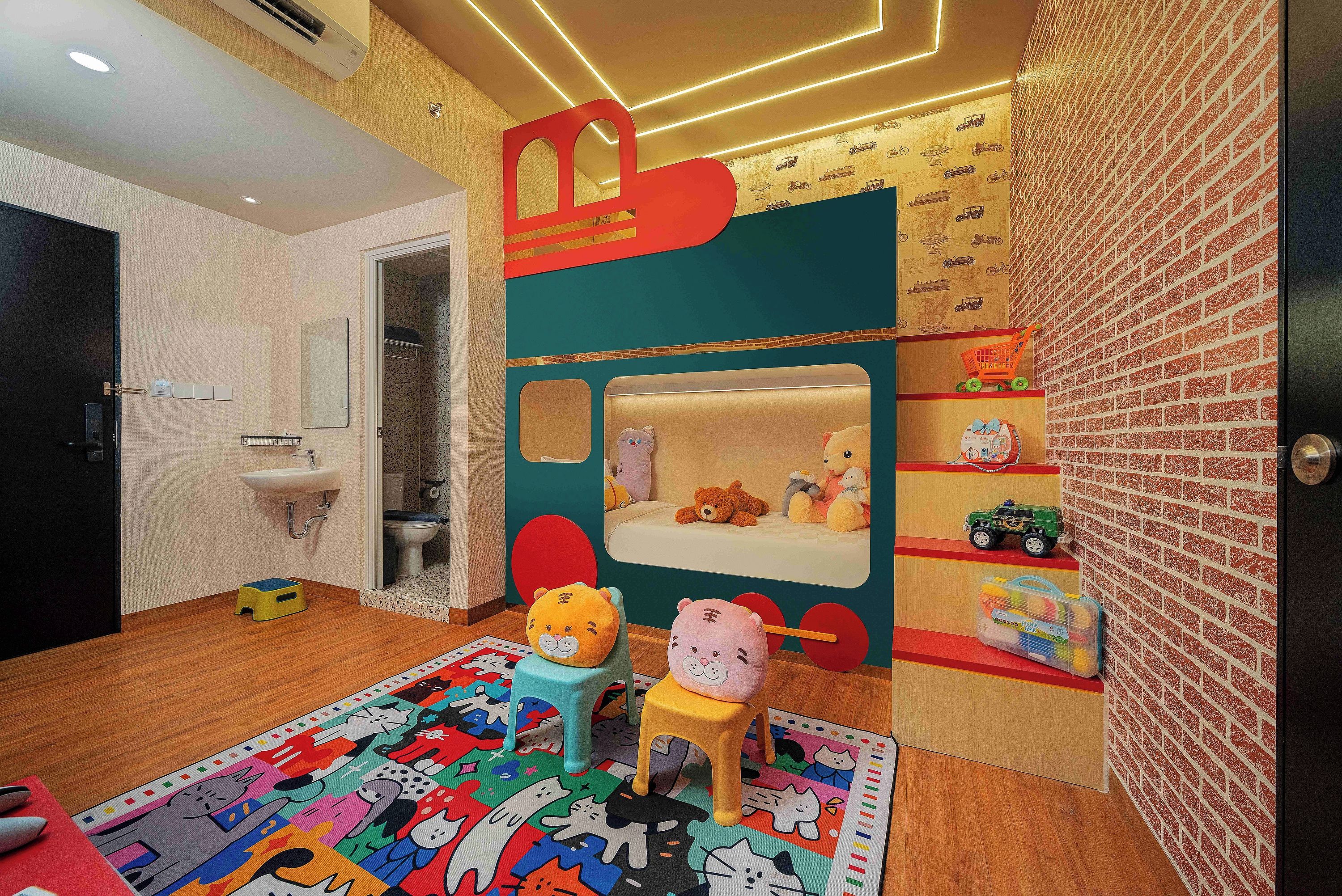 Un cuarto de juegos infantil con una cama, juguetes y una alfombra colorida.