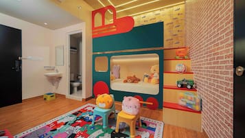 Un cuarto de juegos infantil con una cama, juguetes y una alfombra colorida.