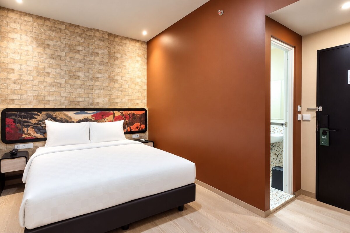 Habitación de hotel con una cama grande, una pared de ladrillo decorativa y una puerta a un balcón.