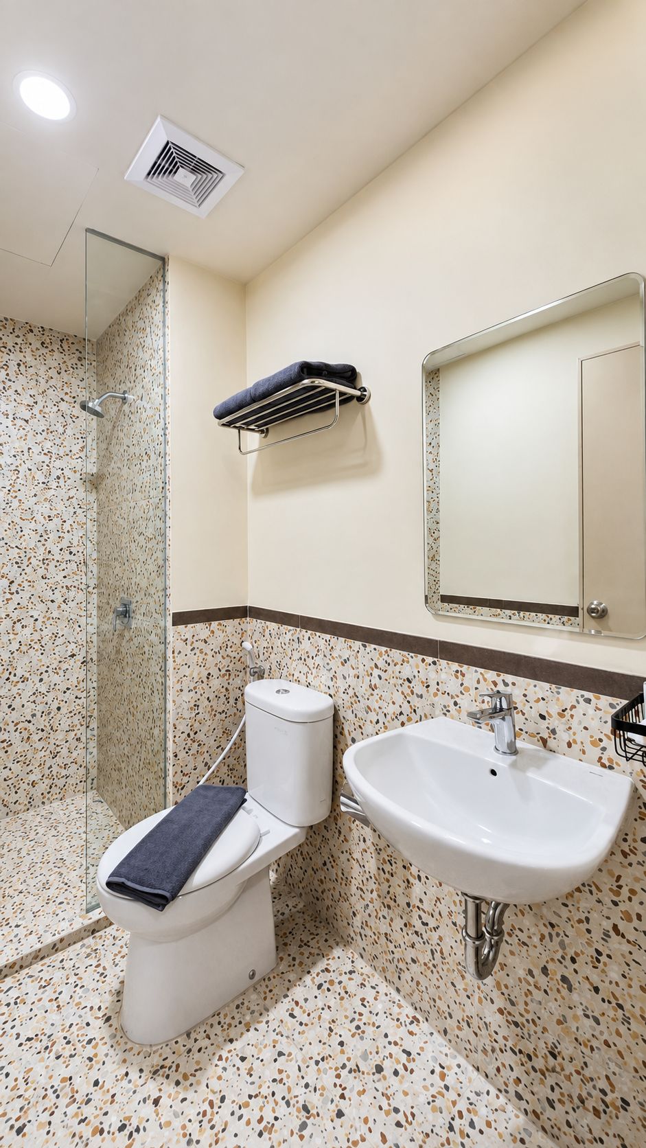 A bathroom with a toilet, sink, shower, and a mirror.