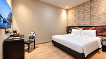 Una habitación de hotel con cama, escritorio, silla y televisión.