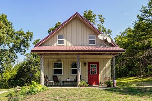 A two-story house with a red door, a covered porch, and satellite dishes. - Ozarks Escape! Farmhouse w/ Fire Pit + Trails (Aurora)