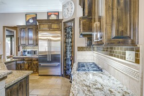 Una cocina con un refrigerador de acero inoxidable, un microondas y una estufa a gas.