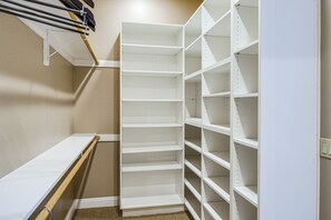 Ein begehbarer Kleiderschrank mit weißen Regalelementen und einer Holzbank.