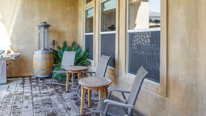 Eine Terrassenfläche mit Holzofen, zwei Korbstühlen, einem kleinen Rundtisch und einem Blumentopf.