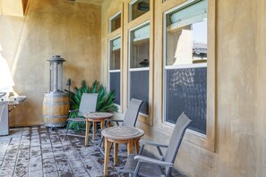 Eine Terrassenfläche mit Holzofen, zwei Korbstühlen, einem kleinen Rundtisch und einem Blumentopf.