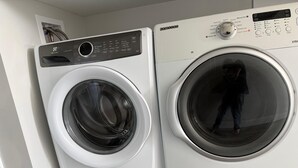 A front-loading washing machine and dryer side by side in a laundry room.
