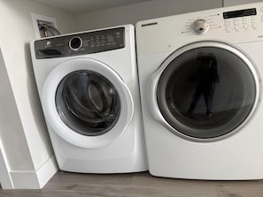 A front-loading washing machine and dryer side by side in a laundry room.