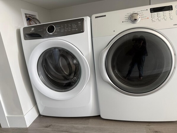 A front-loading washing machine and dryer side by side in a laundry room.