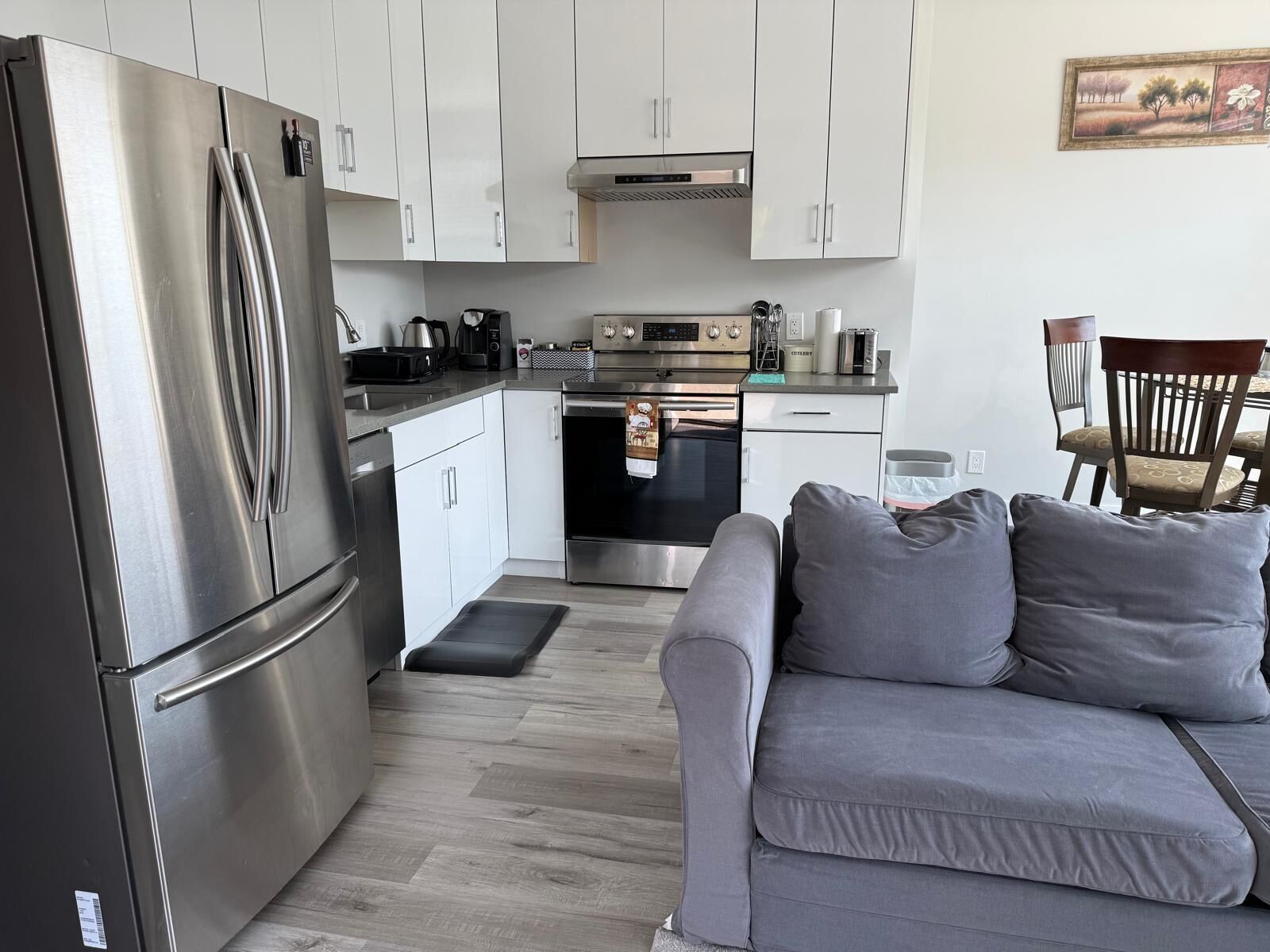A compact kitchen with a stainless steel refrigerator, a built-in oven, and a coffee maker.