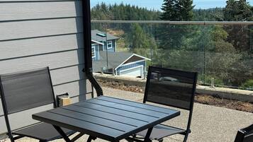Un balcon avec une table et des chaises, donnant sur un quartier résidentiel avec des maisons et des arbres.