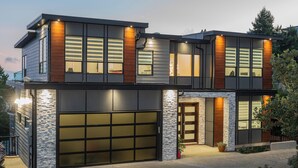 A modern two-story house with a garage, large windows, and a stone facade.
