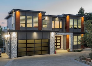 A modern two-story house with a garage, large windows, and a stone facade.