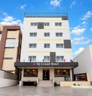 A multi-story hotel with a prominent entrance, a signboard, and a series of windows. - DJ Grand Hotel (Tirupati)