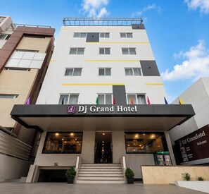 A multi-story hotel with a prominent entrance, a reception desk, and a clear sky in the background. - DJ Grand Hotel (Tirupati)
