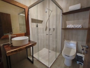 Ein modernes Badezimmer mit einer Duschkabine, einem Holzwaschtisch und einer Toilette.