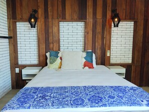 Ein Bett mit weißem Kopfteil, einer blauen Bettdecke und zwei Wandleuchten.