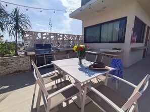 An outdoor patio with a white table, chairs, a grill, and a decorative fence. - Habitacion con balcon (Playa del Carmen)