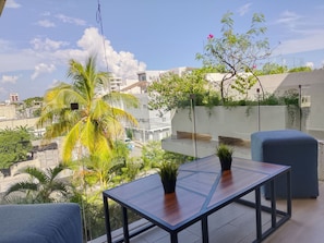 Ein Balkon mit Holztisch, zwei Blumentöpfen und einem blauen Stuhl.