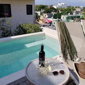 Ein Pool auf dem Dach mit Tisch, Flasche und Hut.